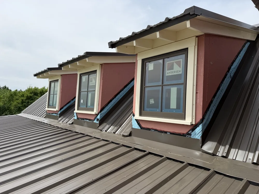 Three shed dormers on the bronze standing-seam roof