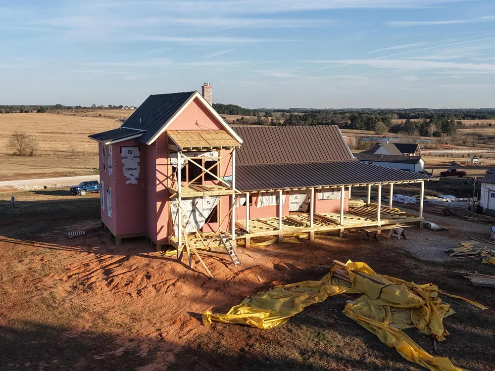 Golden-hour aerial of a two-story farmhouse among East Texas fields
