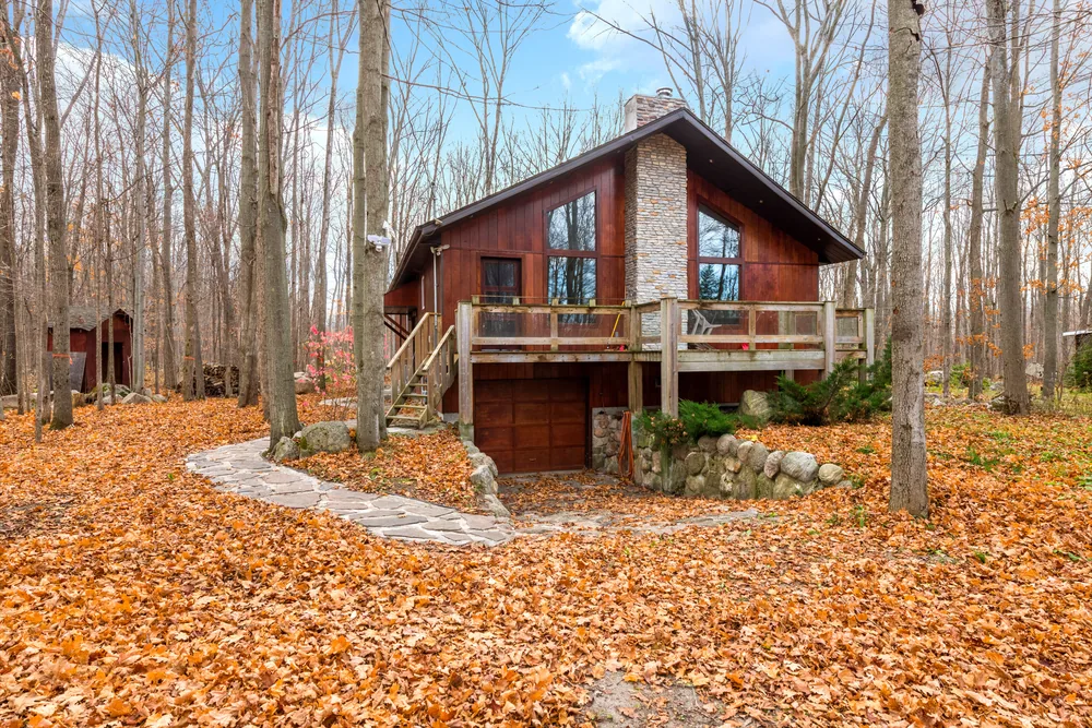 The Ravenhill Home — wood-sided chalet with stone chimney in an autumn maple forest, Tiny, Ontario